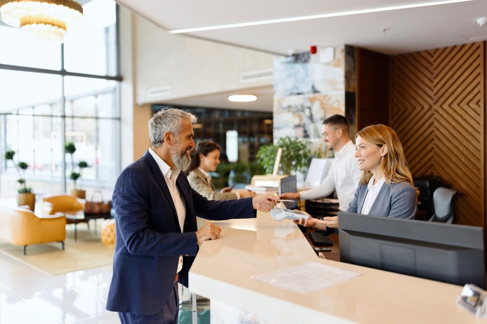 man in suit checking into hotel at front desk